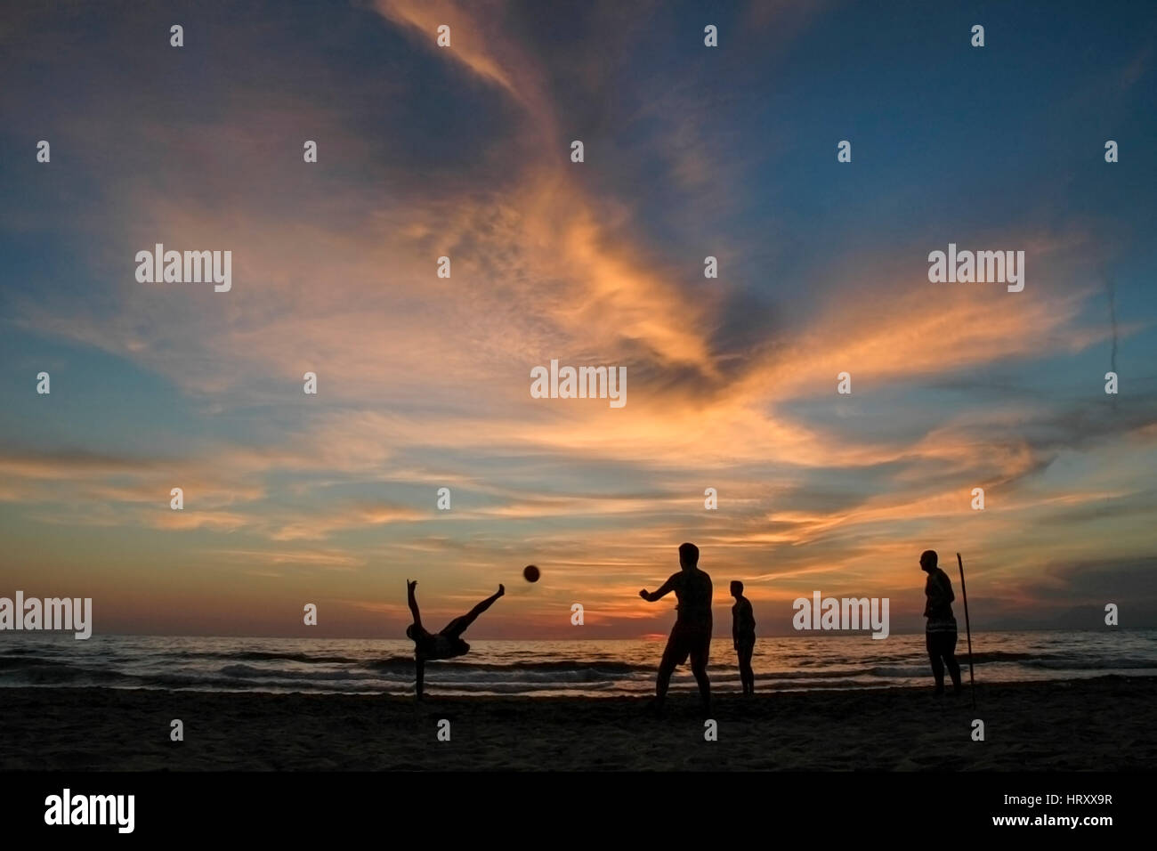 Action as a man bicycle kicks a ball on the beach Stock Photo