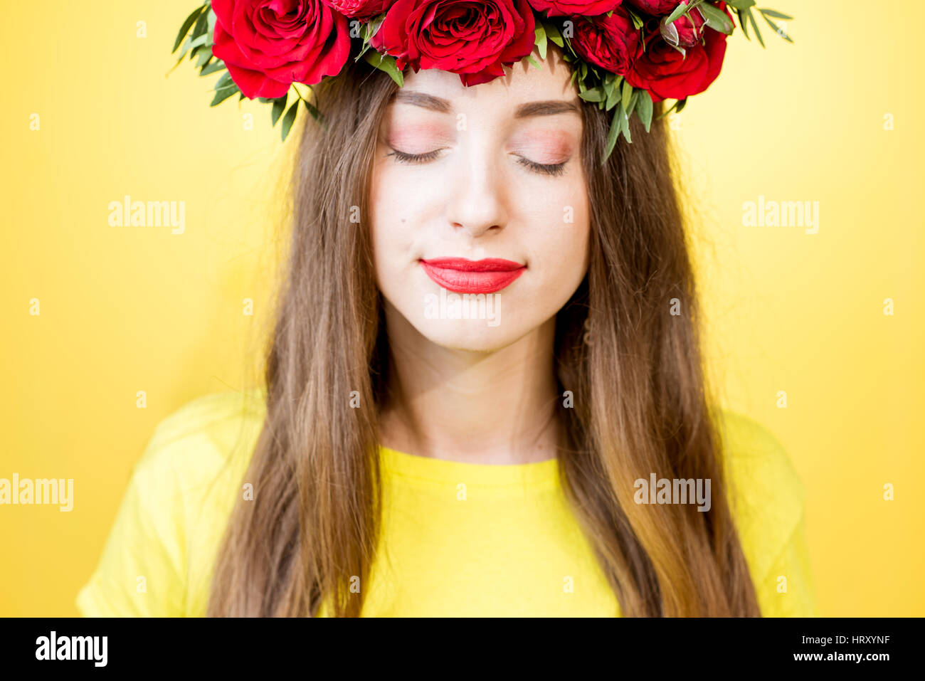 Close-up portrait of a beautiful woman with wreath made of red roses on ...