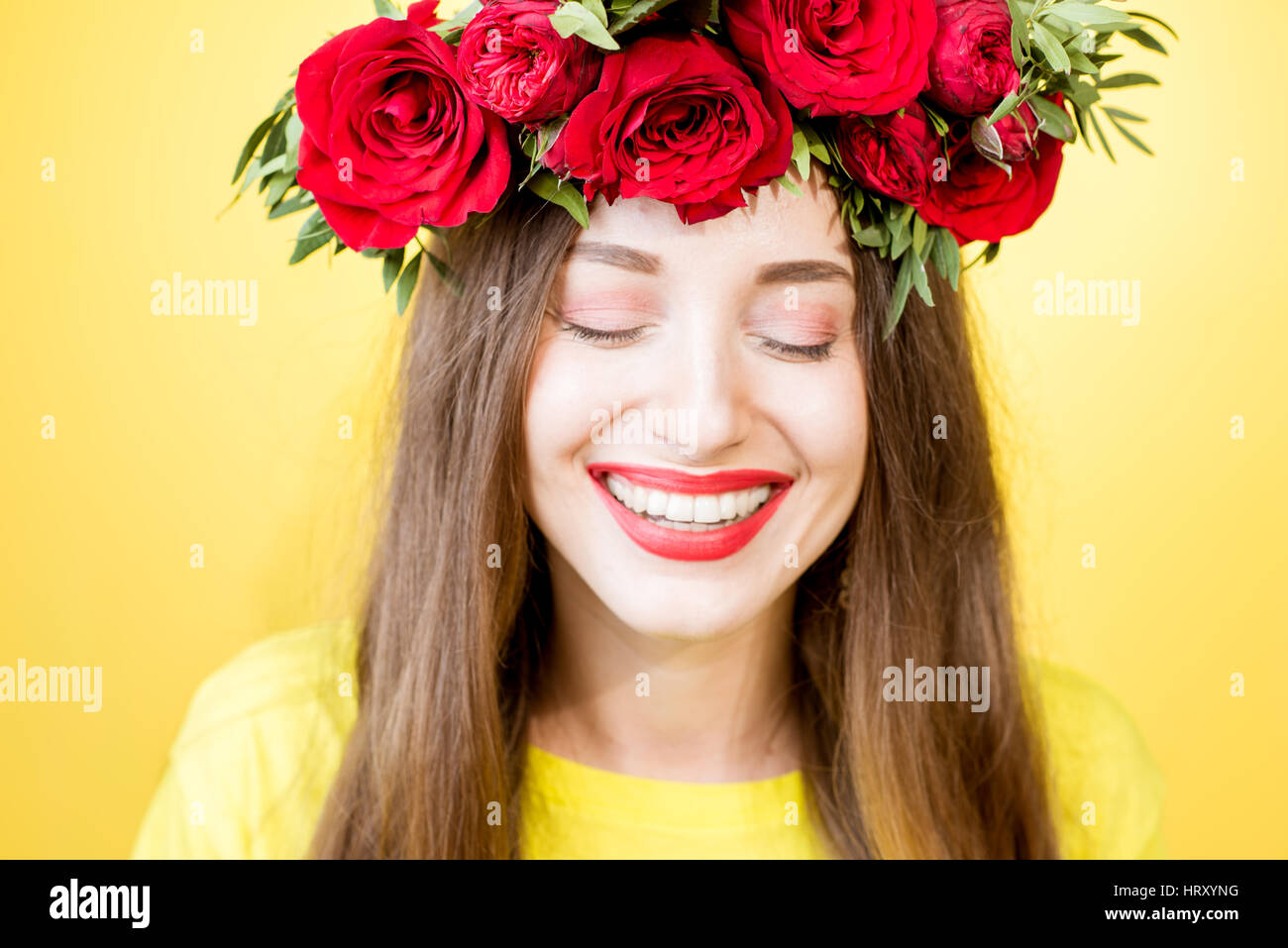 Close-up portrait of a beautiful woman with wreath made of red roses on ...