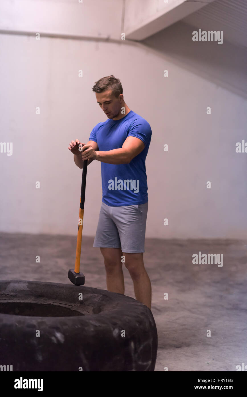 Sledgehammer Tire Hits young muscular man workout at gym with hammer and tractor tire Stock