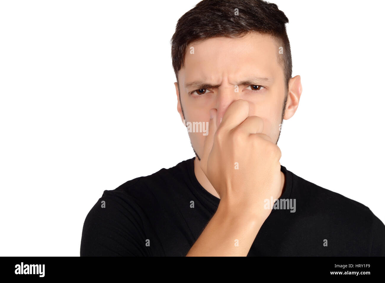 Portrait of young man holding his nose against a bad smell. Isolated white background. Stock Photo