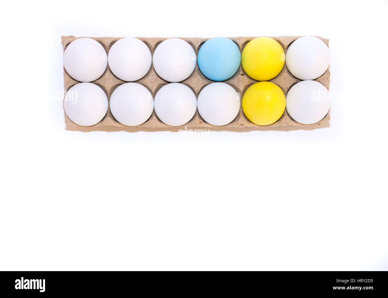 Two Easter eggs dyed yellow, one egg dyed blue and nine white hen's eggs in a tan cardboard