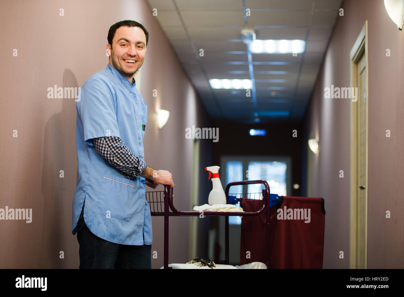 Man cleaning hotel hall wearing blue coat Stock Photo