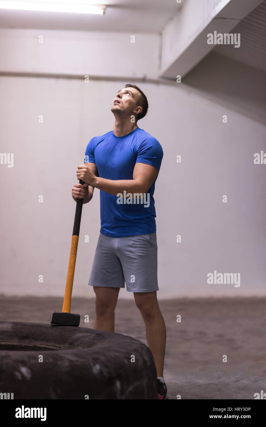 Sledgehammer Tire Hits young muscular man workout at gym with hammer and tractor tire Stock