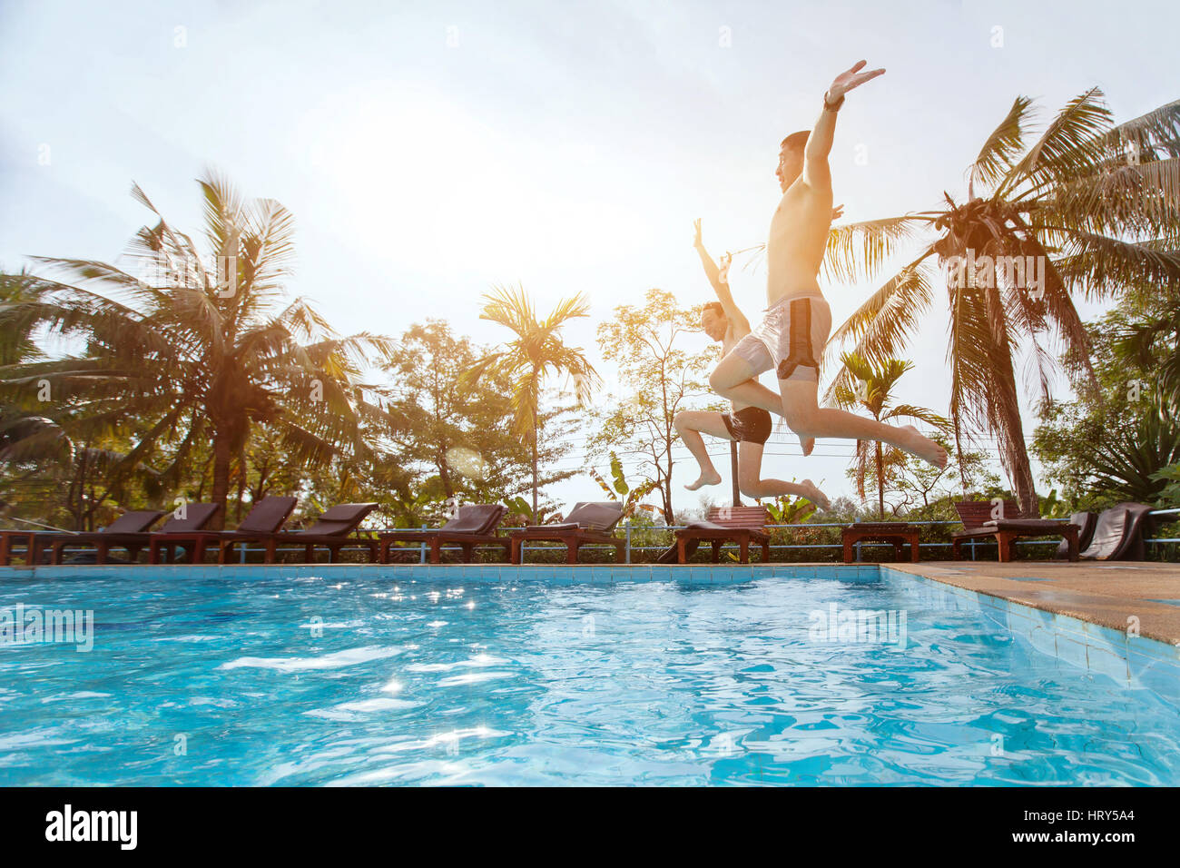 people jumping to the swimming pool, beach holidays, friends having fun together Stock Photo