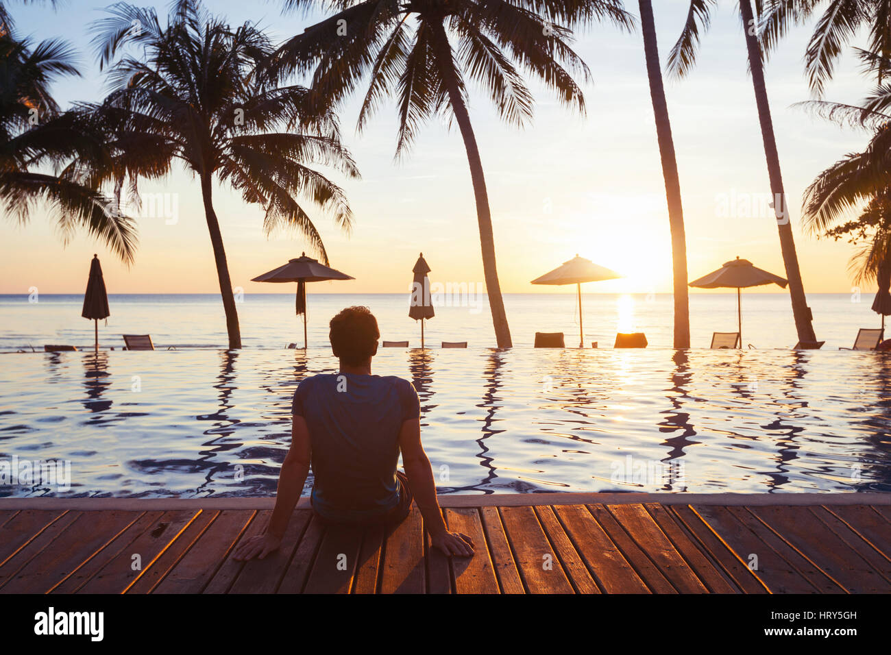 relaxation on the beach, young man enjoying beautiful sunset in luxury hotel near swimming pool Stock Photo