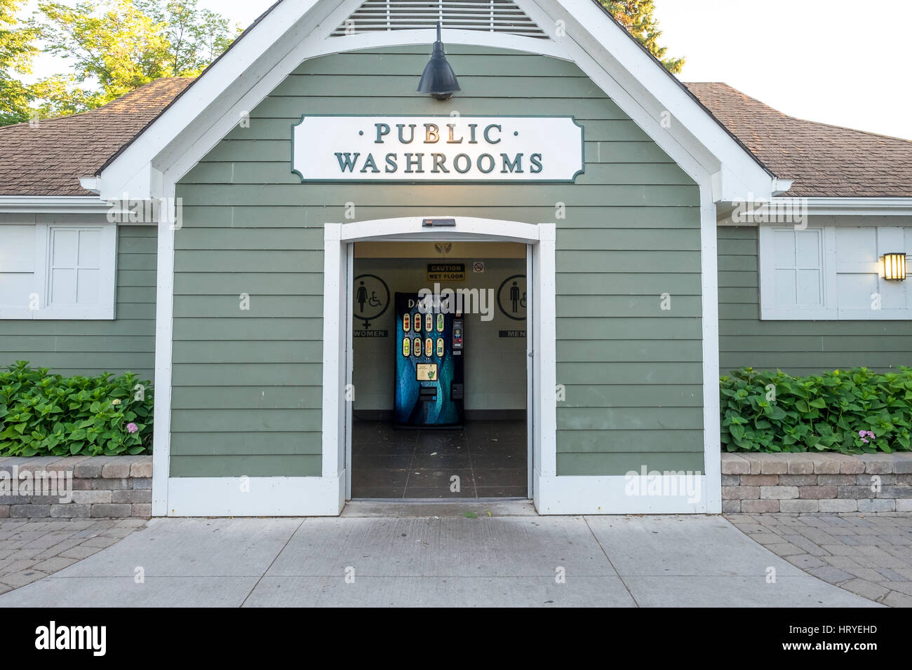 A public washroom building painted green with white trim with a vending