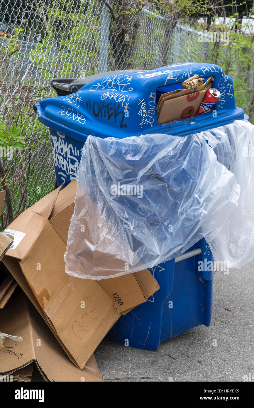 A blue recycle garbage bin overflowing with trash Stock Photo - Alamy