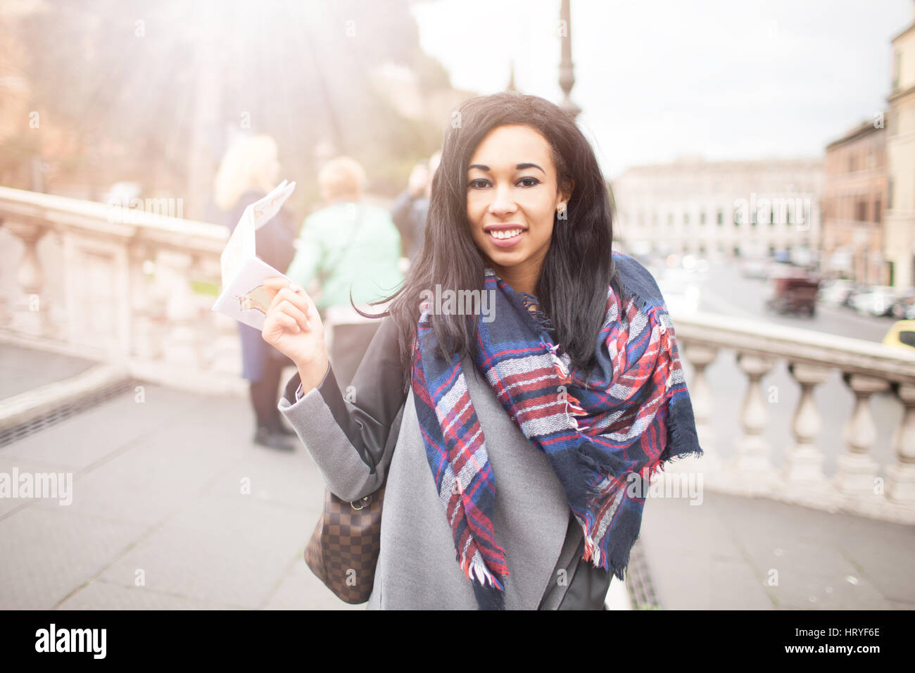Young beautiful mixed raced woman smiling and looking camera with map in the right hand, in Rome, Italy. Concept of traveling, modern lifestyle, conte Stock Photo
