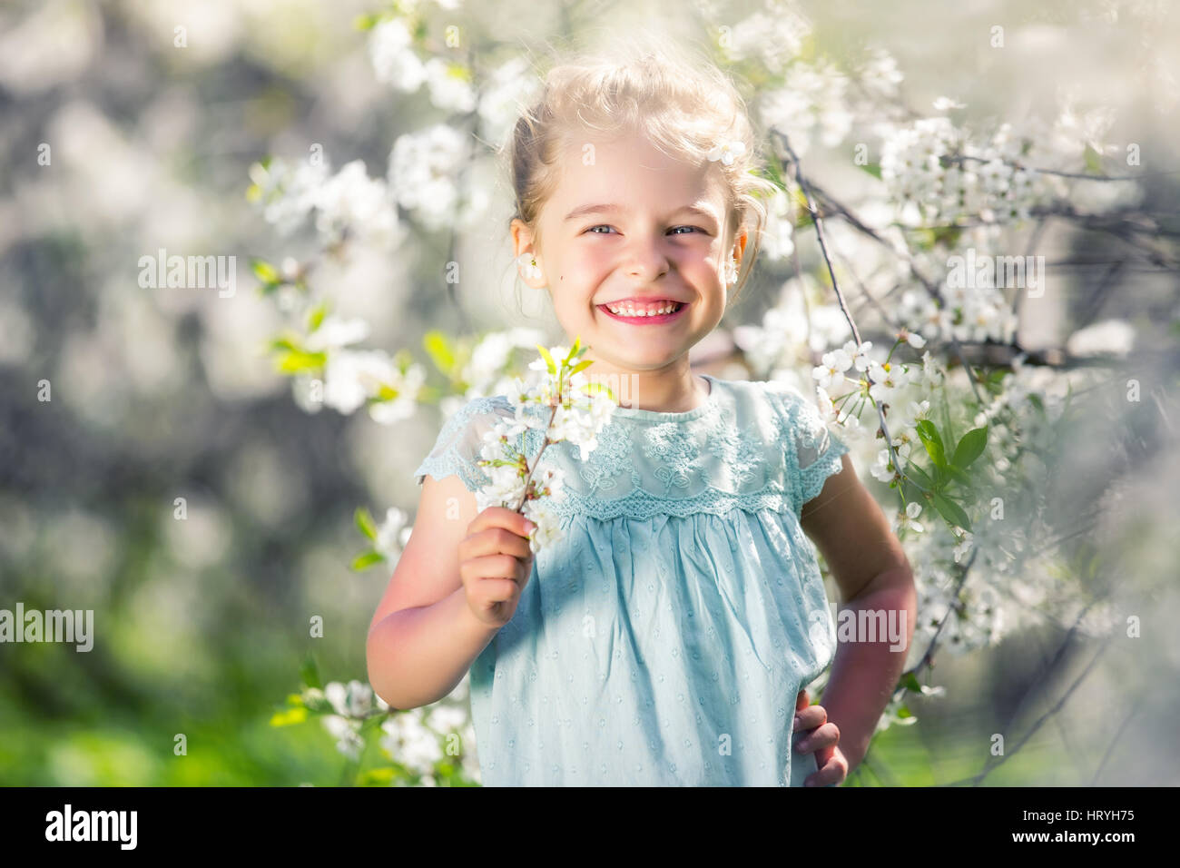 Happy little girl in cherry blossom garden Stock Photo - Alamy