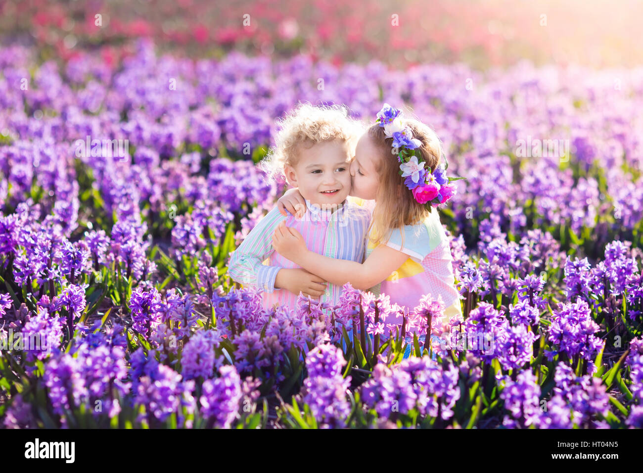 Kids gardening. Children play outdoors in hyacinths meadow. Little girl and boy, brother and sister, work in the garden, planting hyacinth flowers, wa Stock Photo