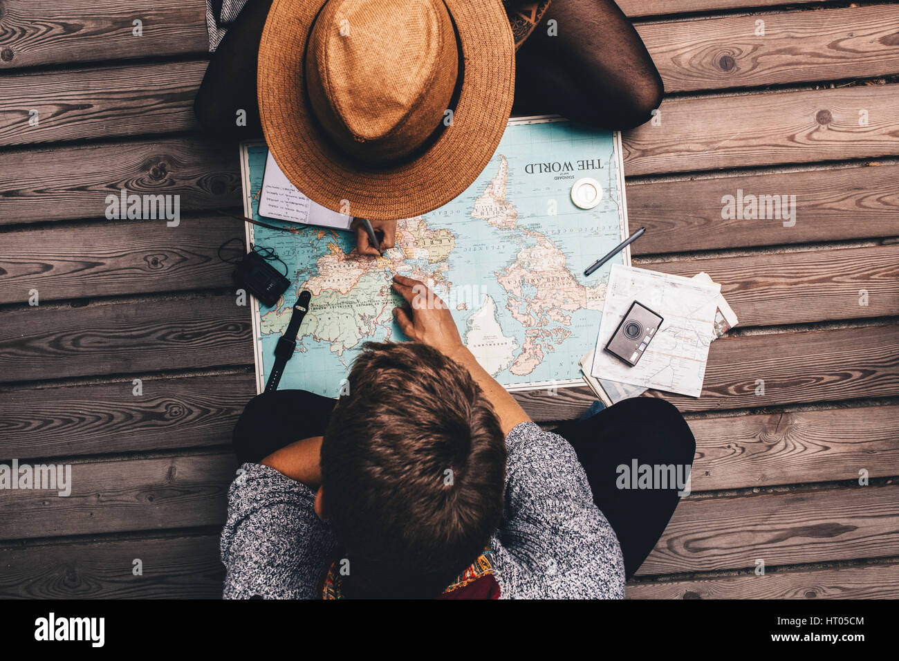Man and woman making vacation plans using the world map. Couple sitting by the map and exploring it. Stock Photo