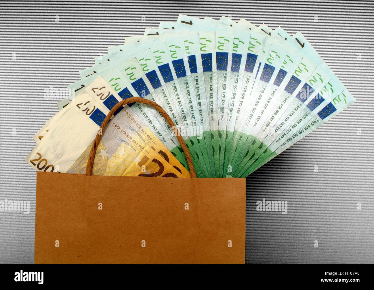 Symbolbild Geld ausgeben beim Einkauf, Papiertuete mit Geld - symbolic for expensive shopping Stock Photo