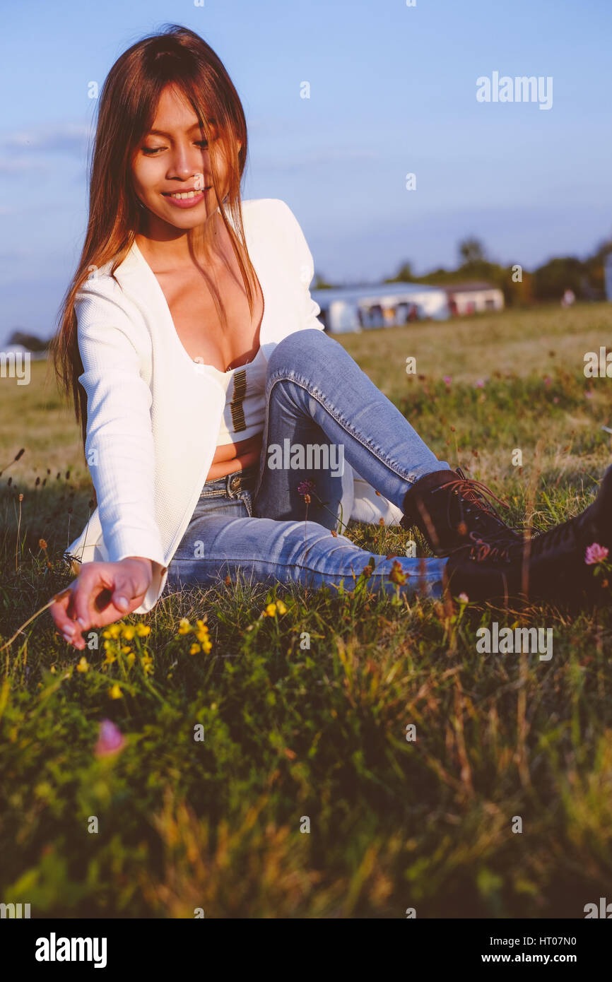 Beautiful girl playing with the flowers on the field during sunset Stock Photo