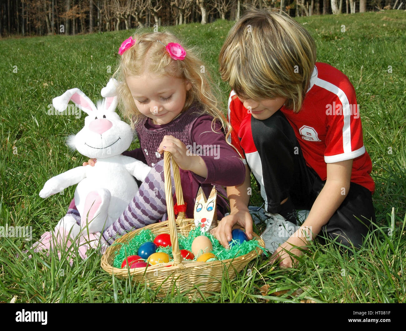 Zwei Kinder mit Osternest in der Wiese - children with Easter nest in meadow Stock Photo