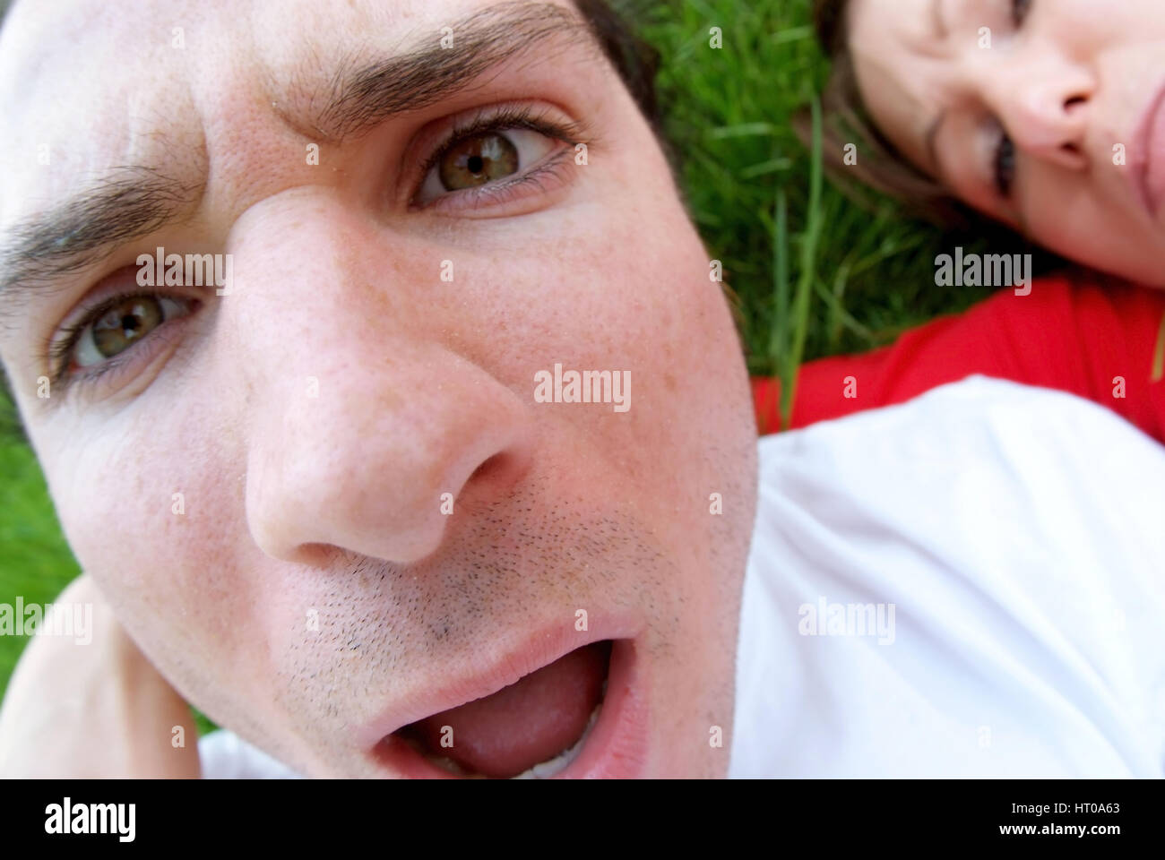 empoerter, junger Mann mit Freundin in Wiese liegend - disgusted young man with woman Stock Photo