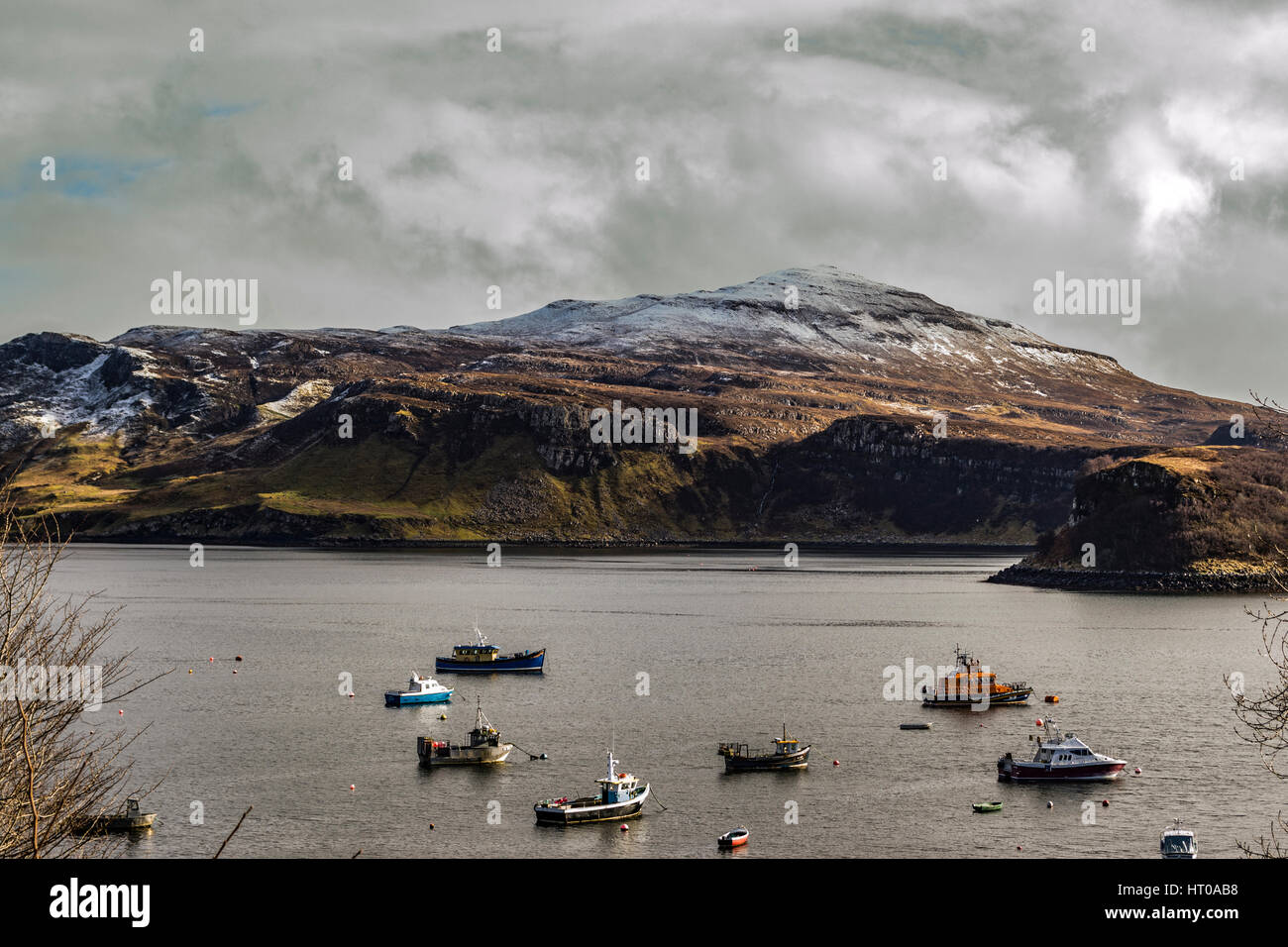 Ben Tianavaig and Sound of Raasay across Portree Harbour, on the Isle of Skye, Scotland, against a dramatic sky Stock Photo