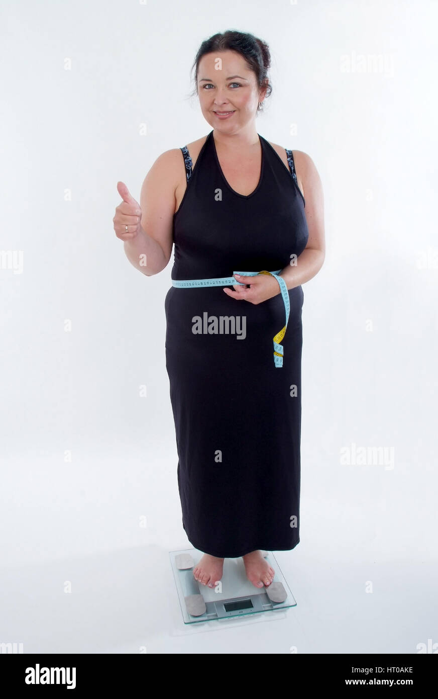 selbstbewusste, mollige Frau steht auf Waage - self-confident, chubby woman on scale Stock Photo