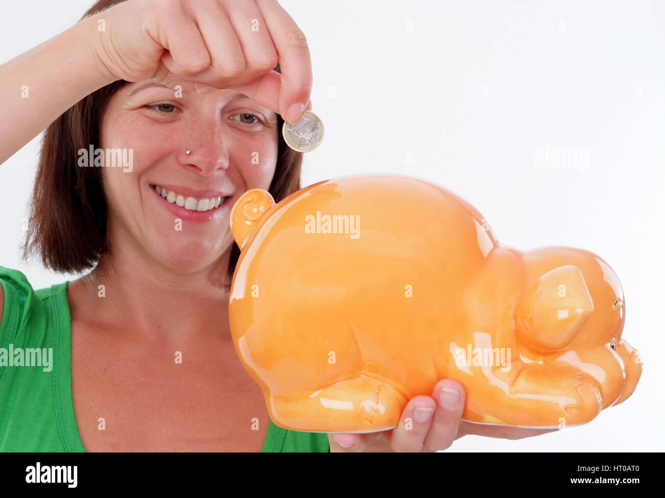 Frau wirft Euromuenze in Sparschwein - woman saving money Stock Photo