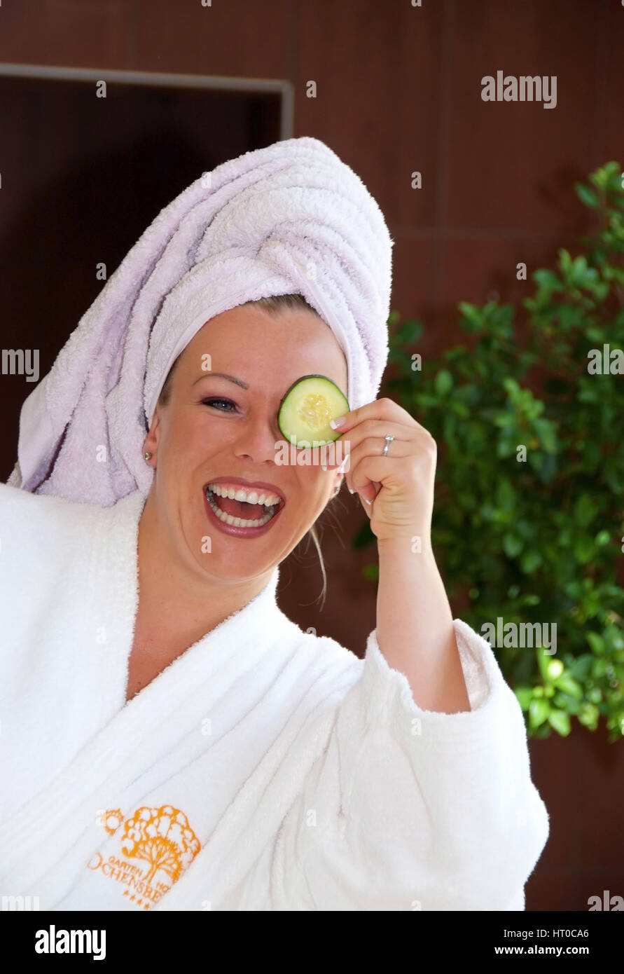 Junge, vitale Frau h?lt sich Gurkenscheibe vor das Gesicht - young, vital woman with cucumber Stock Photo