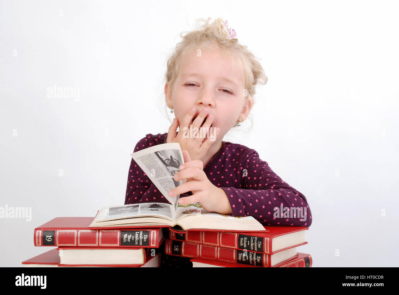Gelangweiltes, kleines M?dchen sitzt ?ber Buchstapel und g?hnt - bored, little girl with books Stock Photo