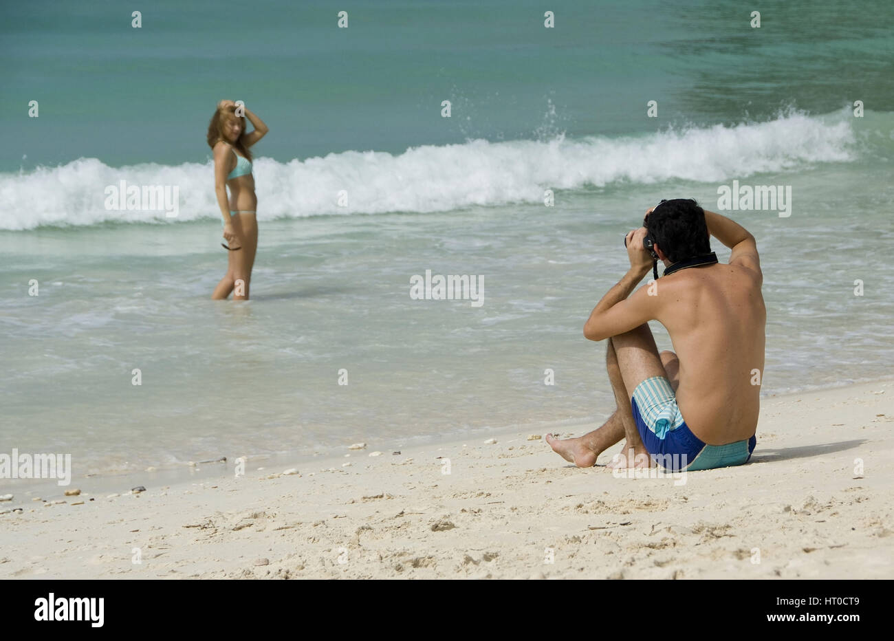 Mann fotografiert Frau im Bikini am Meeresufer - photographer with model on the beach Stock Photo
