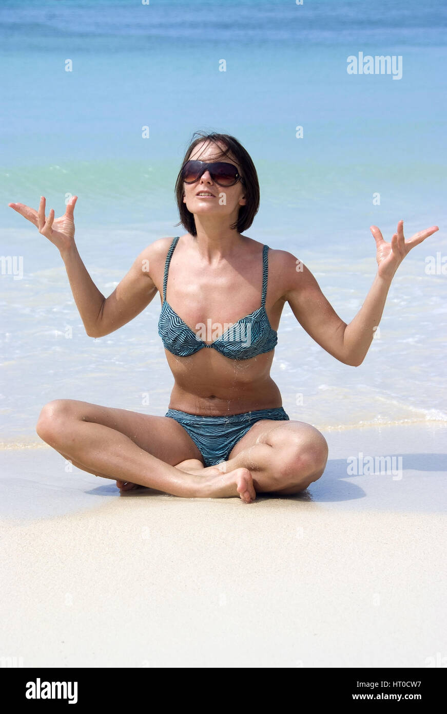 Frau macht Joga am Sandstrand - woman does yoga on the beach Stock Photo