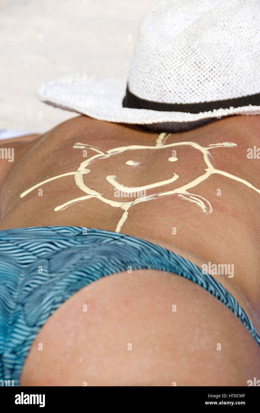 Frau beim Sonnen mit Sonnencreme in Form einer Sonne am R¸cken - woman suns with sun care Stock Photo