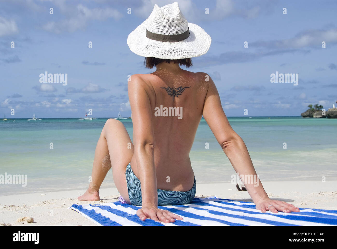 Junge Frau sitzt oben ohne am Strand - woman on the beach Stock Photo