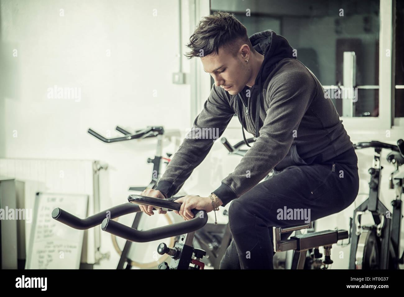 Young man exercising in gym: spinning on stationary bike Stock Photo
