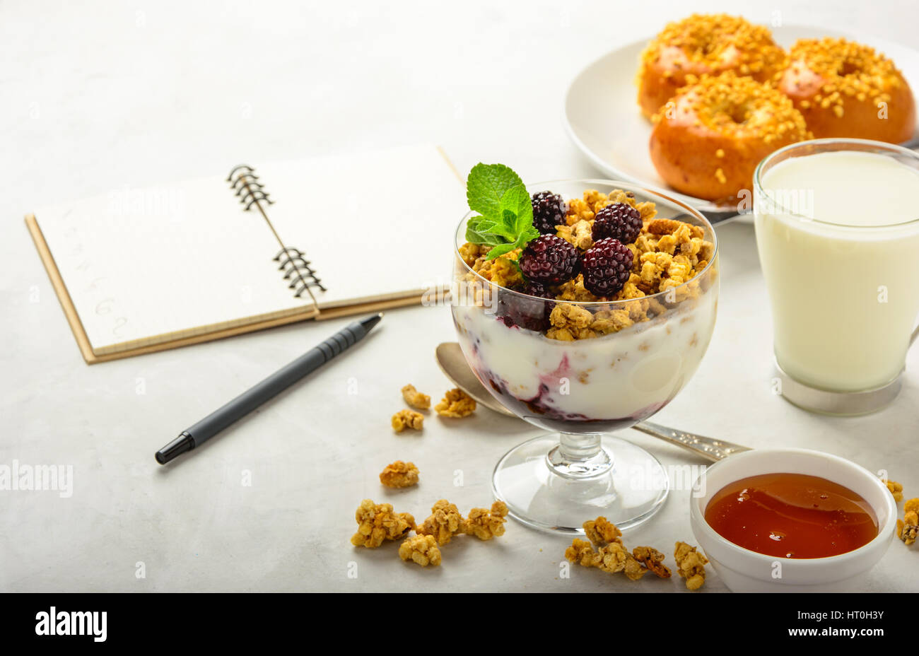 Delicious and healthy breakfast of granola, buns brioche, honey and milk on a light background . Soft focus. Stock Photo