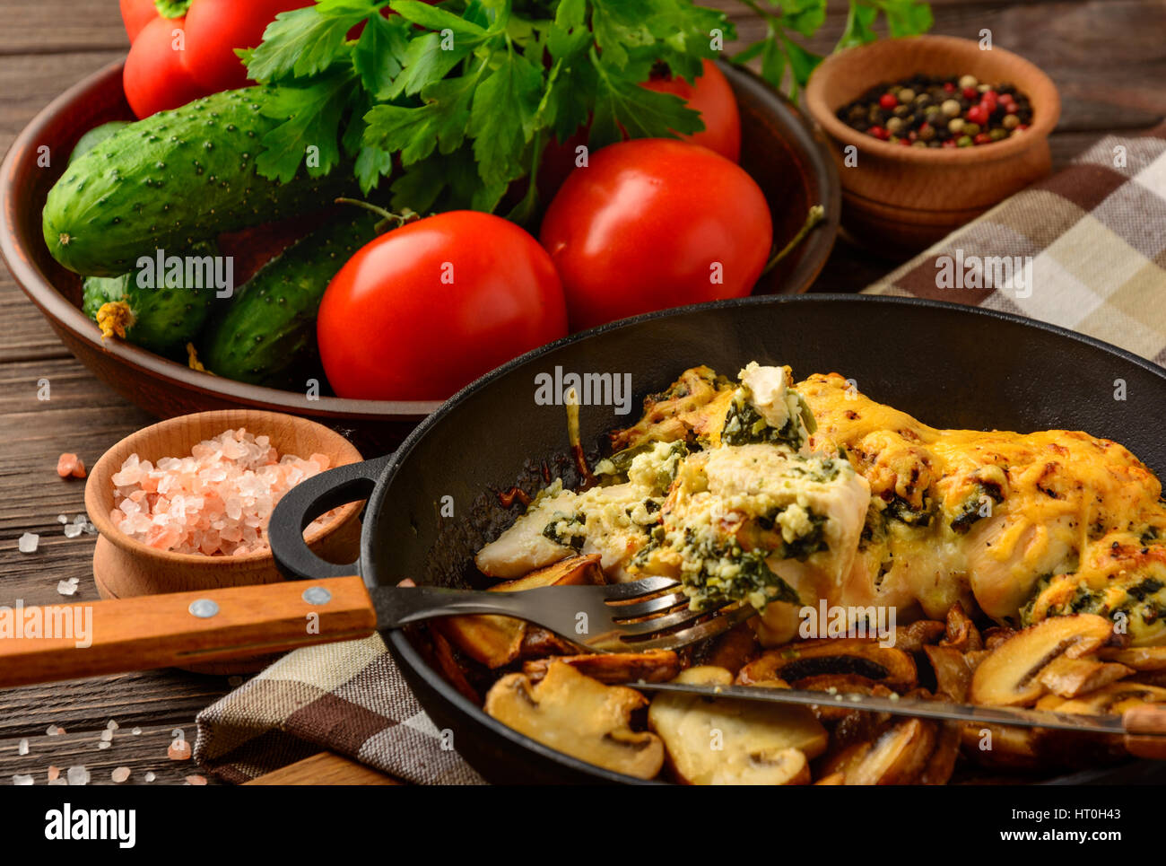 Baked chicken breast stuffed with spinach and cheese with vegetables on a dark background of a wooden table. Stock Photo