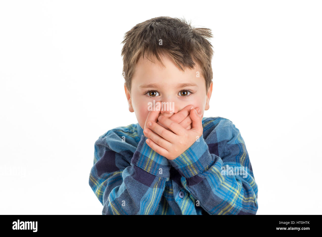 Little boy covering mouth with his hands looking straight ahead. Scared, stubborn or afraid of saying too much. Isolated on a white background. Stock Photo