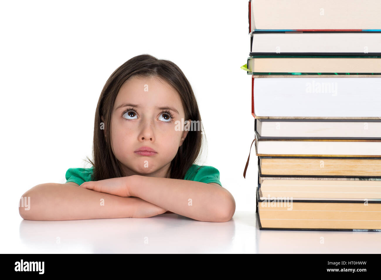 School girl looking up at the pile of books. Isolated on a white background. Stock Photo