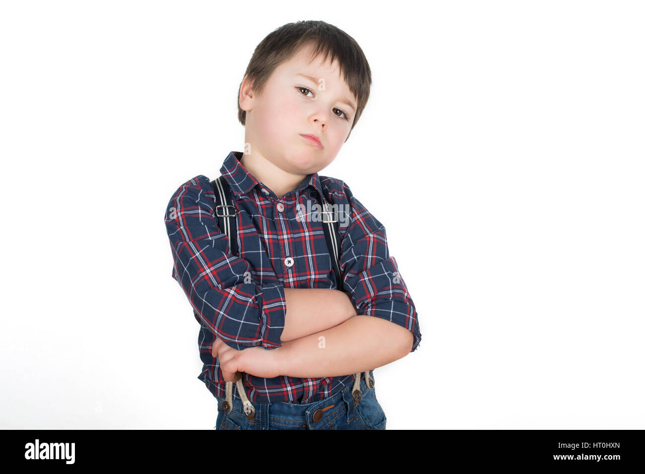Little stubborn boy standing with crossed hands pretending he is a tough guy. Isolated on a white background. Stock Photo