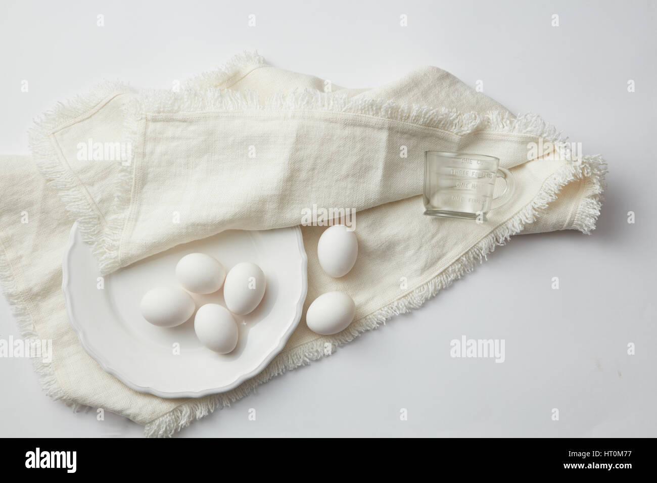 Top view of raw chicken eggs in plate on napkin on white table Stock Photo