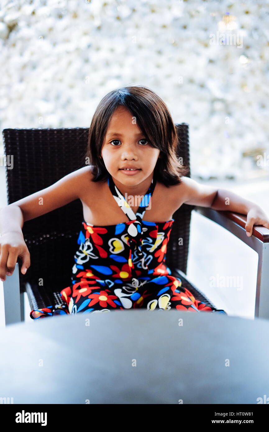 Young little cute girl sitting on the chair alone waiting Stock Photo