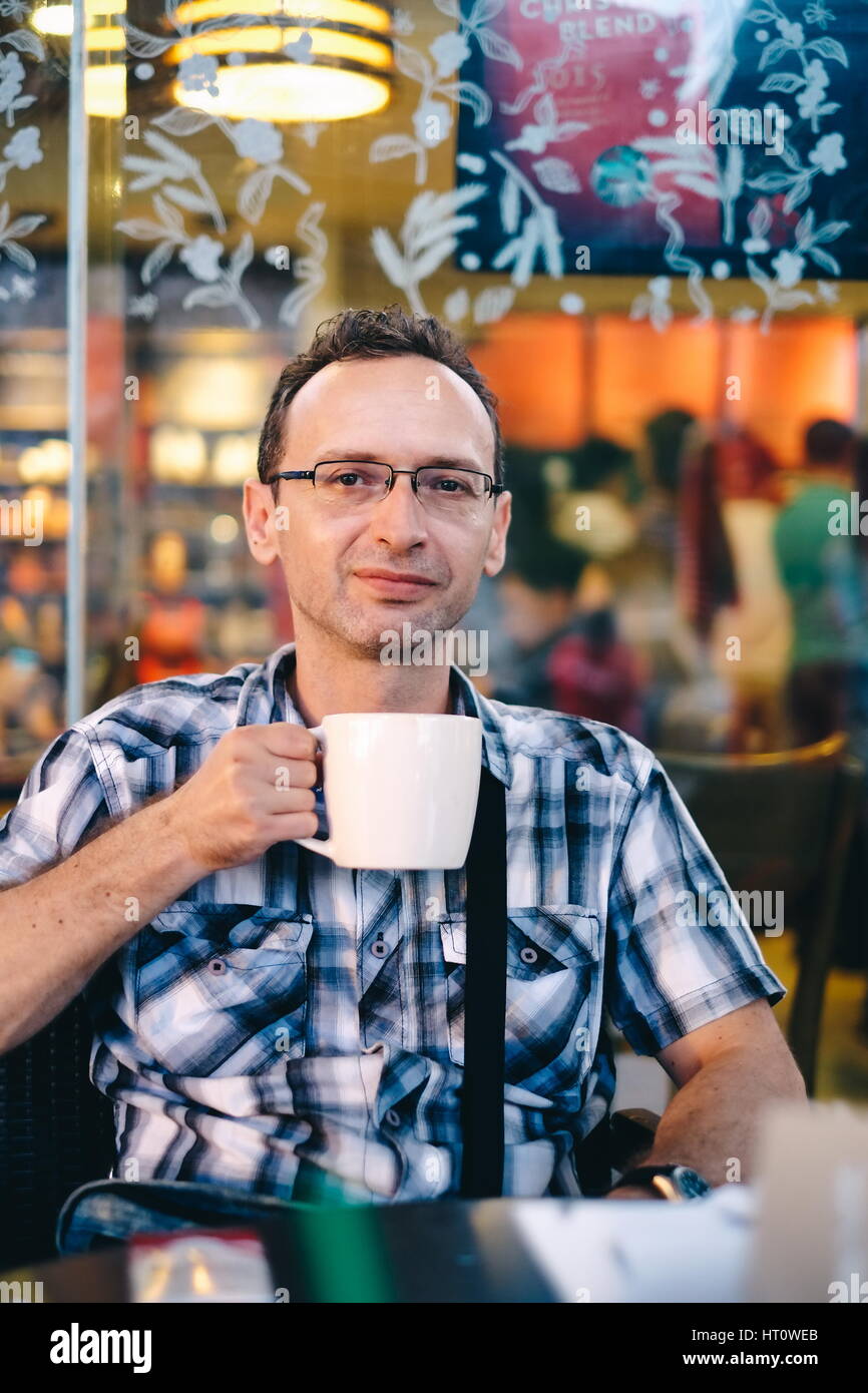 Handsome man in a cafe outside drinking coffee Stock Photo