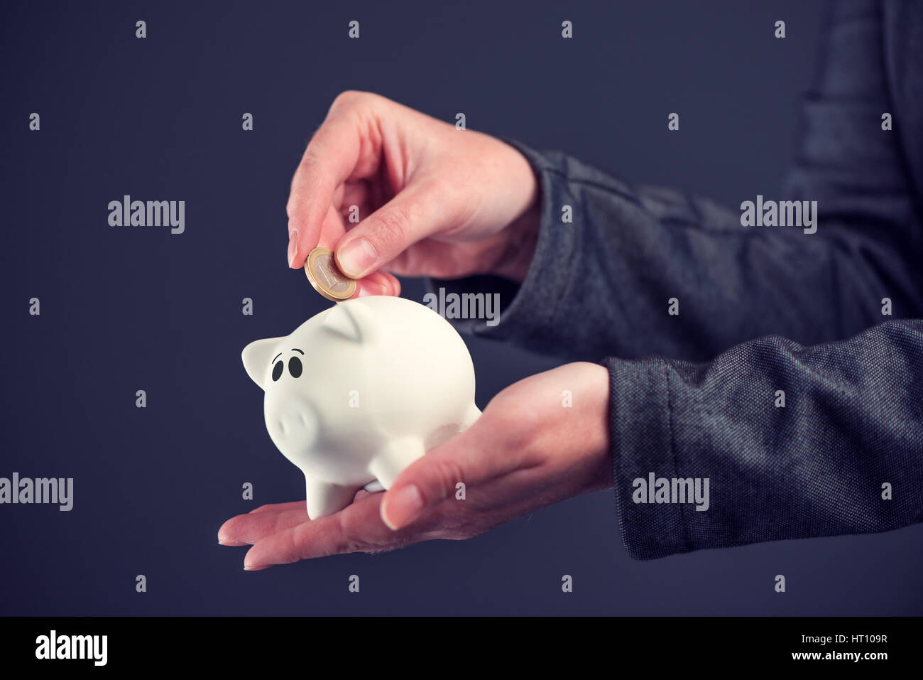 Businesswoman putting one euro coin in piggy bank, money savings and home budget concept Stock Photo