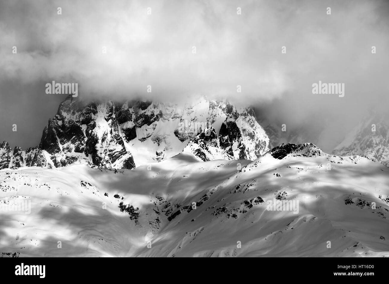 Black and white view on Mount Ushba in fog at sun winter day. Caucasus Mountains. Svaneti region of Georgia. Stock Photo