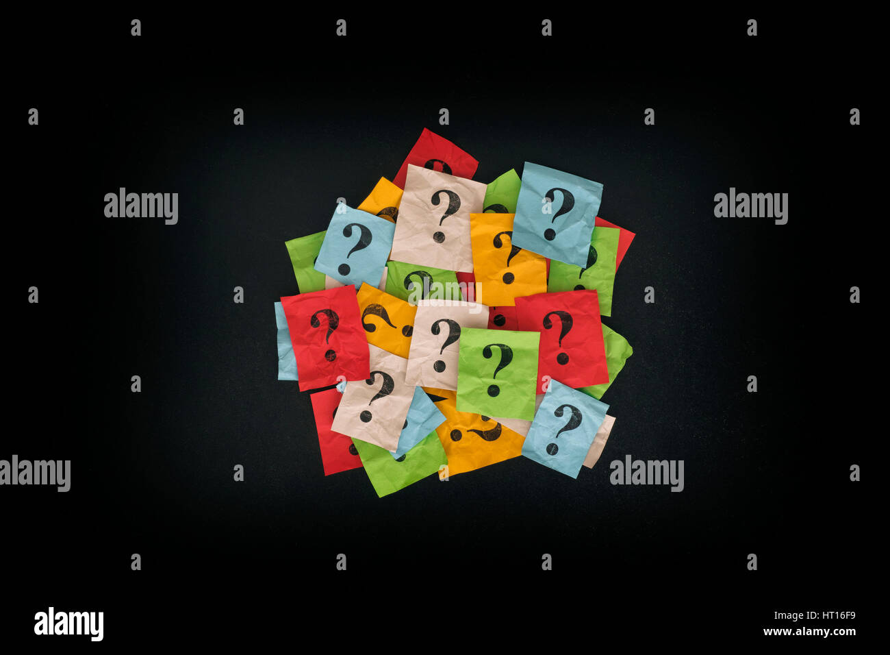 Too Many Questions. Pile of colorful paper notes with question marks on blackboard. Closeup. Stock Photo