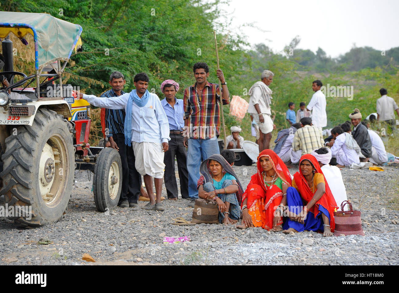 A group of Rajasthani people from the Bhil Tribe sit and stand around their  tractor Stock Photo