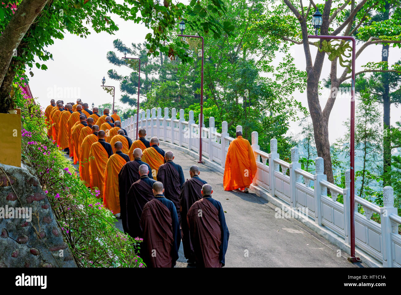 Monks walking along a small street with nature Stock Photo