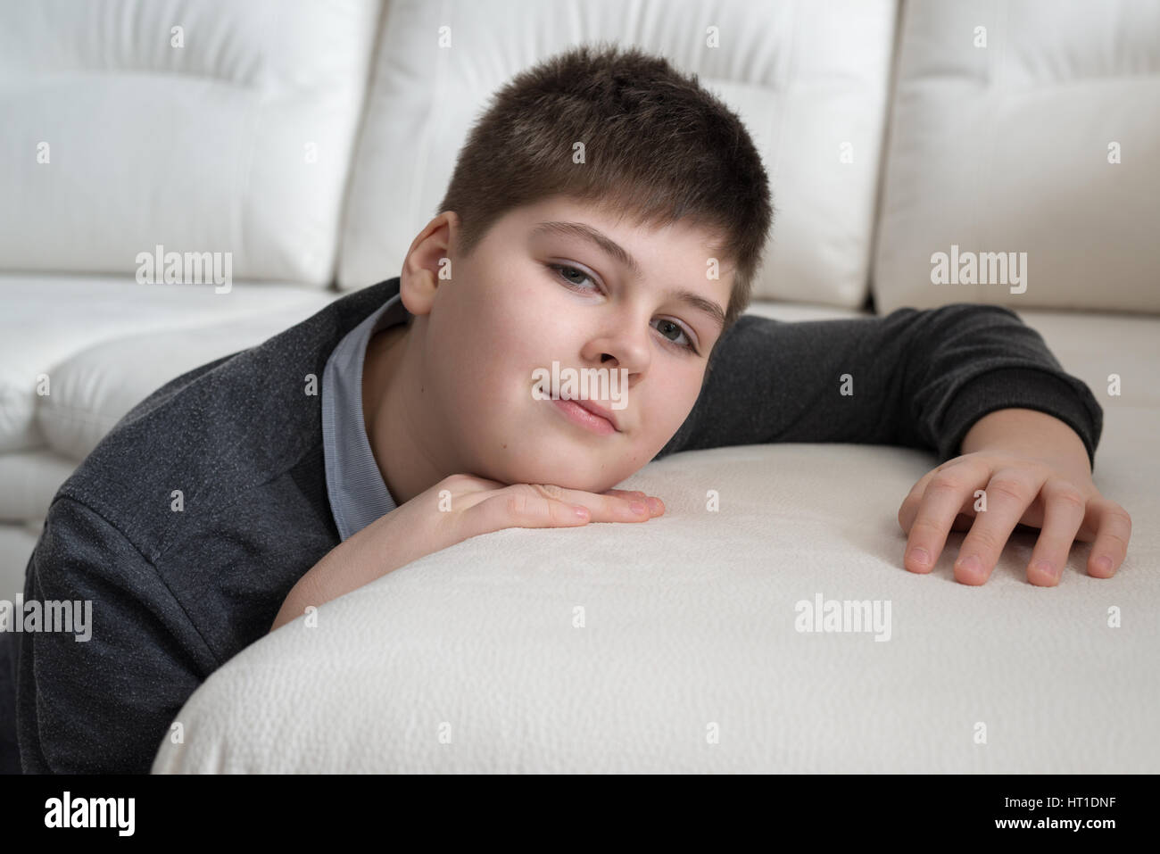 13 year boy sitting near the sofa in room Stock Photo