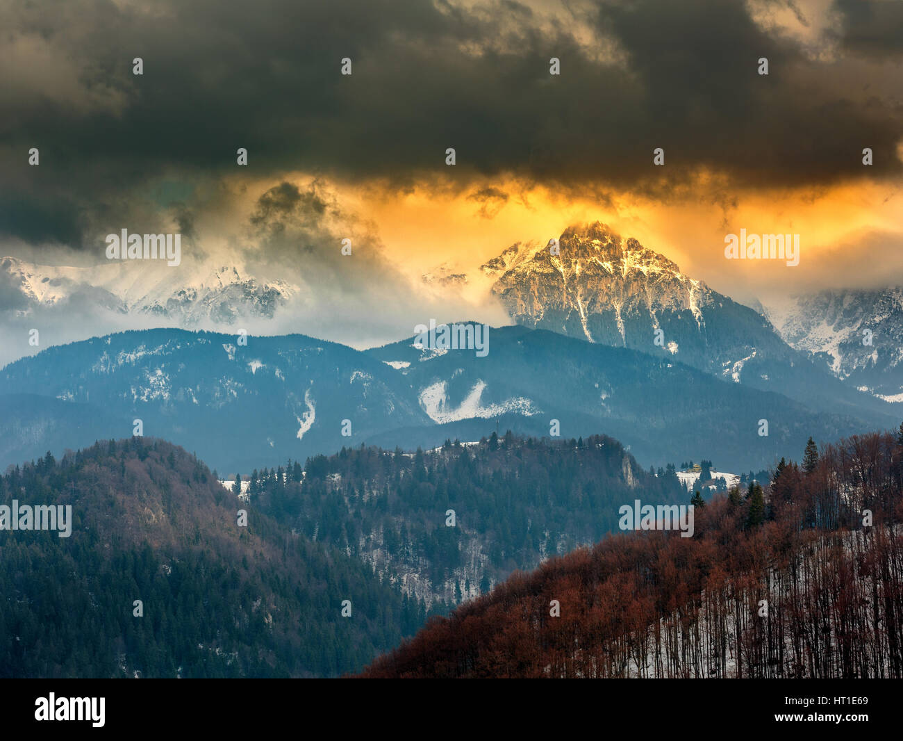 Sunset over mountains peaks with clouds Stock Photo - Alamy
