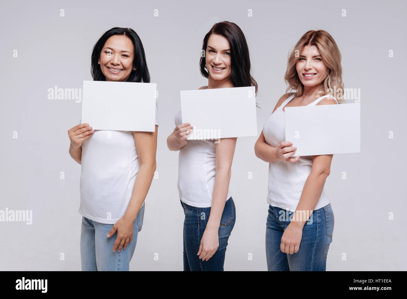 Unique is beautiful. Active charismatic alluring women holding pieces of paper in their hands while working with a professional photographer in a stud Stock Photo