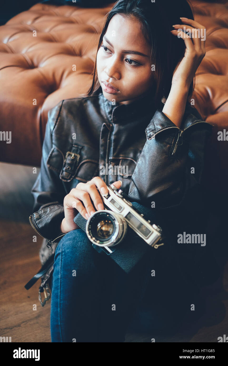 Hipster girl holding camera in leather jacket Stock Photo