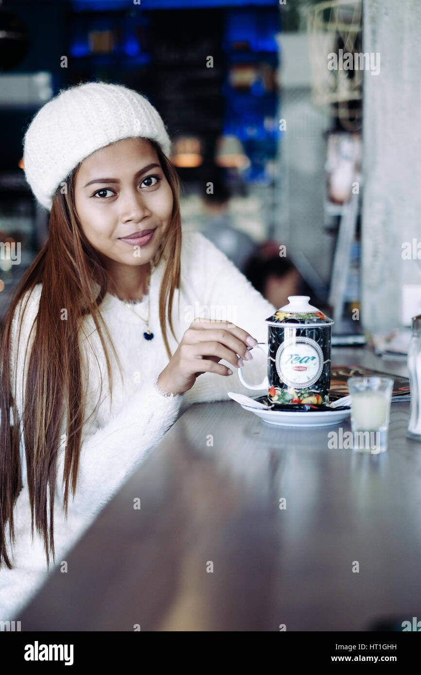 Beautiful young girl wearing white clothes driniking tea in a bar Stock Photo