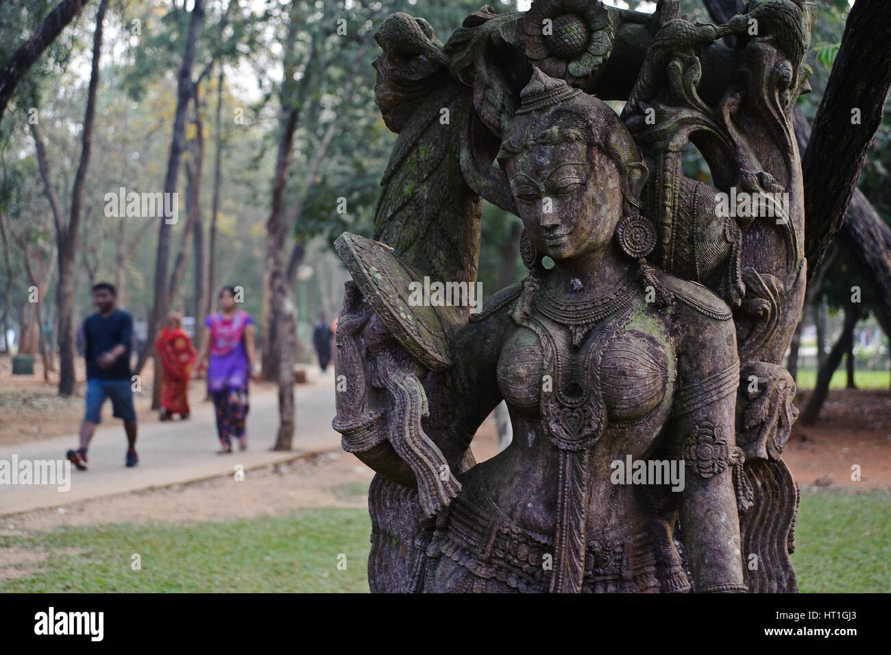 People are exercising in a park. In the foreground, a sculpture representing a woman ( India) Stock Photo