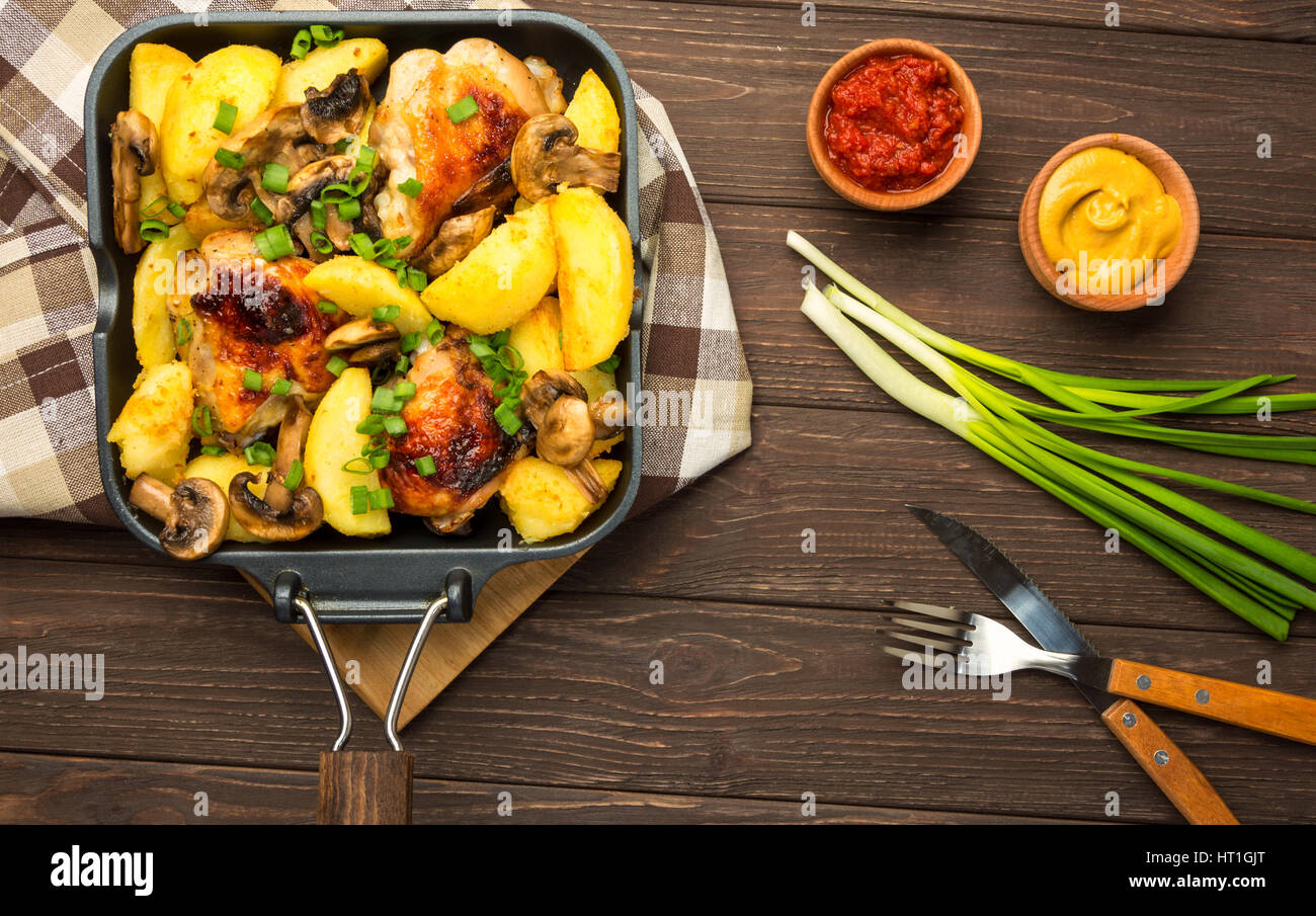 Dinner with baked chicken legs with olives spiced with aromatic herbs and potatoes with mushrooms on a rustic background. Top view, copy space. Stock Photo